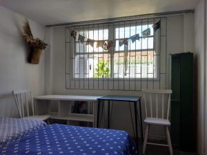 een slaapkamer met een bed en een raam en een tafel en stoelen bij ANNANDA in Florianópolis