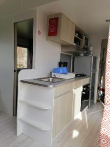 a small kitchen with a sink and a refrigerator at trigano sublima in Litteau