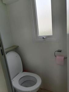 La salle de bains est pourvue de toilettes blanches et d'une fenêtre. dans l'établissement trigano sublima, à Litteau