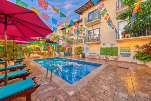 einen Hotelpool mit Stühlen und Sonnenschirmen in der Unterkunft Casa Maria Hotel Boutique & Gallery Adults Only in Puerto Vallarta