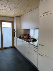 a kitchen with white cabinets and a large window at Ferienhaus Lumnezia Lux in Cumbels