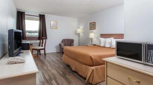 a hotel room with a bed and a desk with a television at Best Stay Inn in Melville