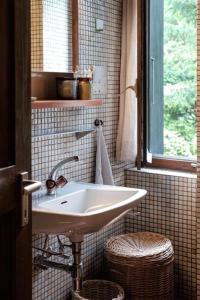 baño con lavabo blanco y ventana en La Stalla - Mid-Century Rustico, en Calpiogna