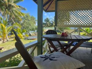 einen Holztisch und Stühle auf einer Veranda mit einem Tisch in der Unterkunft Paparei Beachfront Bungalows, Aitutaki in Arutanga