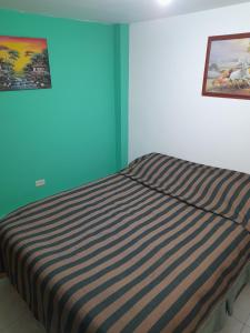 Una cama en una habitación con una manta a rayas. en Mi hospedaje, en Bogotá