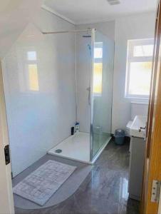 a white bathroom with a shower and a sink at Teach Dunmore in the heart of Donegal Gaeltacht. in Falcarragh