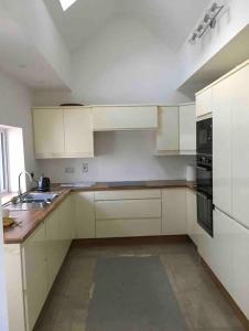 Una cocina con gabinetes blancos y un fregadero. en Teach Dunmore in the heart of Donegal Gaeltacht., en Falcarragh