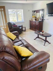a living room with a brown leather couch and a table at Teach Dunmore in the heart of Donegal Gaeltacht. in Falcarragh