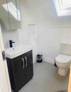 a white bathroom with a toilet and a sink at Teach Dunmore in the heart of Donegal Gaeltacht. in Falcarragh