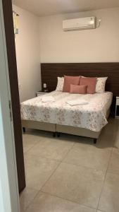 Un dormitorio con una cama con almohadas rosas. en Dom Ângelo Hospedagem, en Bento Gonçalves