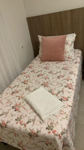 a bed with a pink pillow and a blanket on it at Dom Ângelo Hospedagem in Bento Gonçalves