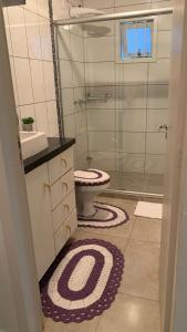 uma casa de banho com um WC e uma cabina de duche em vidro. em Dom Ângelo Hospedagem em Bento Gonçalves