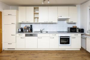 una cocina blanca con armarios blancos y fregadero en L&P Appartement Gerlitzen & Pool - Haus Enzian, en Kanzelhöhe