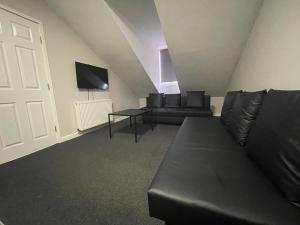 a living room with a black couch and a tv at Hosted By Ryan - 2 Bedroom Apartment in Liverpool