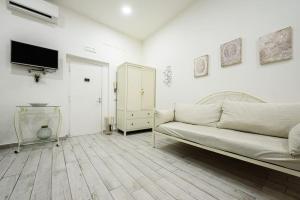 een witte woonkamer met een bank en een tv bij A Due Passi Da Toledo in Napels