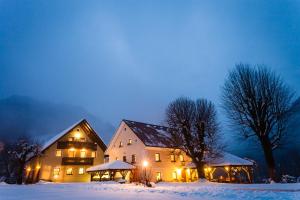 una casa grande en la nieve por la noche en Tourist Farm Zelinc, en Cerkno