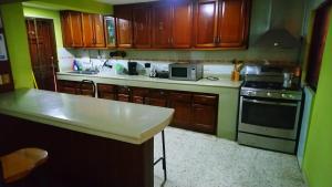 cocina con armarios de madera y horno con fogones en Guest-House alquiler en Santo Domingo