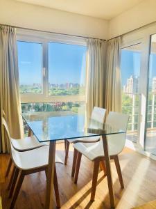 a dining room with a glass table and white chairs at Fantástico depto. con vistas panorámicas in Vicente López +30 photos
