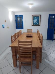 uma mesa de jantar em madeira e cadeiras com portas azuis em CASA DA NINA em Tamandaré