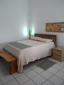 um quarto com uma grande cama branca e uma mesa em CASA DA NINA em Tamandaré