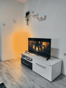 ein Wohnzimmer mit einem Flachbild-TV auf einem weißen Schrank in der Unterkunft SAMI APARTMAN in Niš