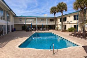 una piscina frente a un edificio con palmeras en The Oceanfront Litchfield Inn 251 en Pawleys Island