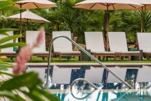 una piscina con sillas y sombrillas en Refúgio da Vila Boutique Hotel & SPA, en Praia do Forte