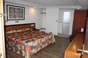 ein Hotelzimmer mit einem Bett, einem Tisch und einer Tür in der Unterkunft Hotel del Sur in Mexiko-Stadt