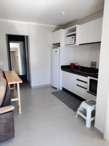 a white kitchen with a refrigerator and a table at Agradável apartamento em bairro silencioso... in Camboriú