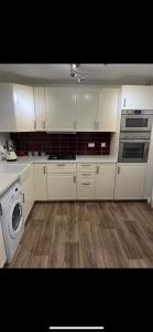 uma cozinha com armários brancos e uma máquina de lavar roupa em Ramulligan Cottage em Cavan