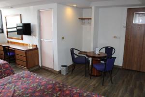 ein Hotelzimmer mit einem Tisch, Stühlen und einem Schreibtisch in der Unterkunft Hotel del Sur in Mexiko-Stadt