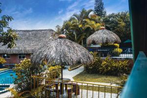 un complejo con piscina y 2 sombrillas de paja en Ecovilla Cali, en Cali