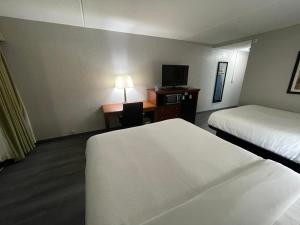 Habitación de hotel con 2 camas y escritorio con TV. en Pine Lake Resort and Banquets, en LaPorte