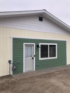 a green garage with a white door and a window at Yellowstone Hideaway in Livingston