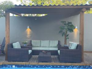 a patio with a couch and tables next to a pool at Pousada Macdonald in Eunápolis