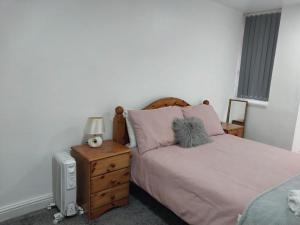 a bedroom with a bed and a dresser with a lamp at Dream Ensuite Rooms in Birmingham