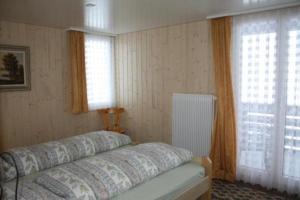 a bedroom with a bed and two windows at Casa Uccello in Wildhaus