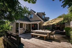 una terraza de madera con mesa y sombrilla en Kings Drive - Wanaka Holiday Home, en Wanaka