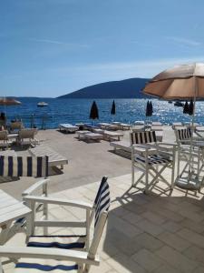 - un groupe de chaises longues et de parasols sur une plage dans l'établissement Villa Vele, à Herceg-Novi