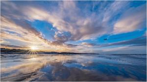 a reflection of the sun in the water on a beach at Playa la Casa in Lossiemouth