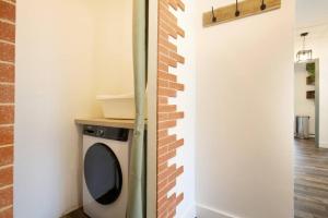 uma máquina de lavar roupa num quarto com uma parede de tijolos em Coeur de Briquettes em Blagnac