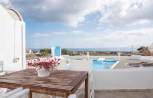 un patio con una mesa de madera y una piscina en Santorini Traditional Suites en Vóthon