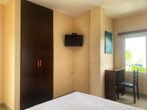 1 dormitorio con 1 cama y TV en la pared en Hotel Boutique Nazo, en Manta