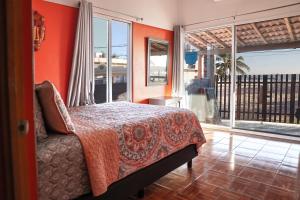 um quarto com paredes cor de laranja, uma cama e uma varanda em Casa Belen - Beautiful Beach View Home on Stone Island em Isla La Piedra