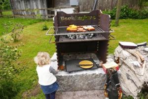a little girl standing in front of a grill at Haus am See - a79839 in Lungern