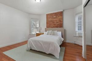 a white bedroom with a bed and a brick wall at Frog Hollow Red Door Retreat in Hartford