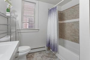 a white bathroom with a toilet and a shower at Frog Hollow Red Door Retreat in Hartford