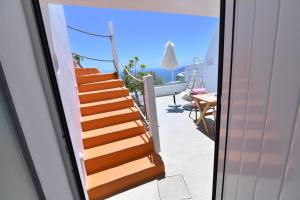 an orange staircase leading to a balcony with a table and chairs at Maria Paradeiso Resorts in Imerovigli