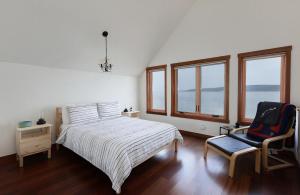 1 dormitorio con 1 cama, 1 silla y ventanas en WhidbeyBeachHouse, an Oceanfront Getaway on a Private Beach, en Langley