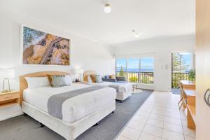 a bedroom with two beds and a balcony at Coast Motel and Apartments in Port Noarlunga